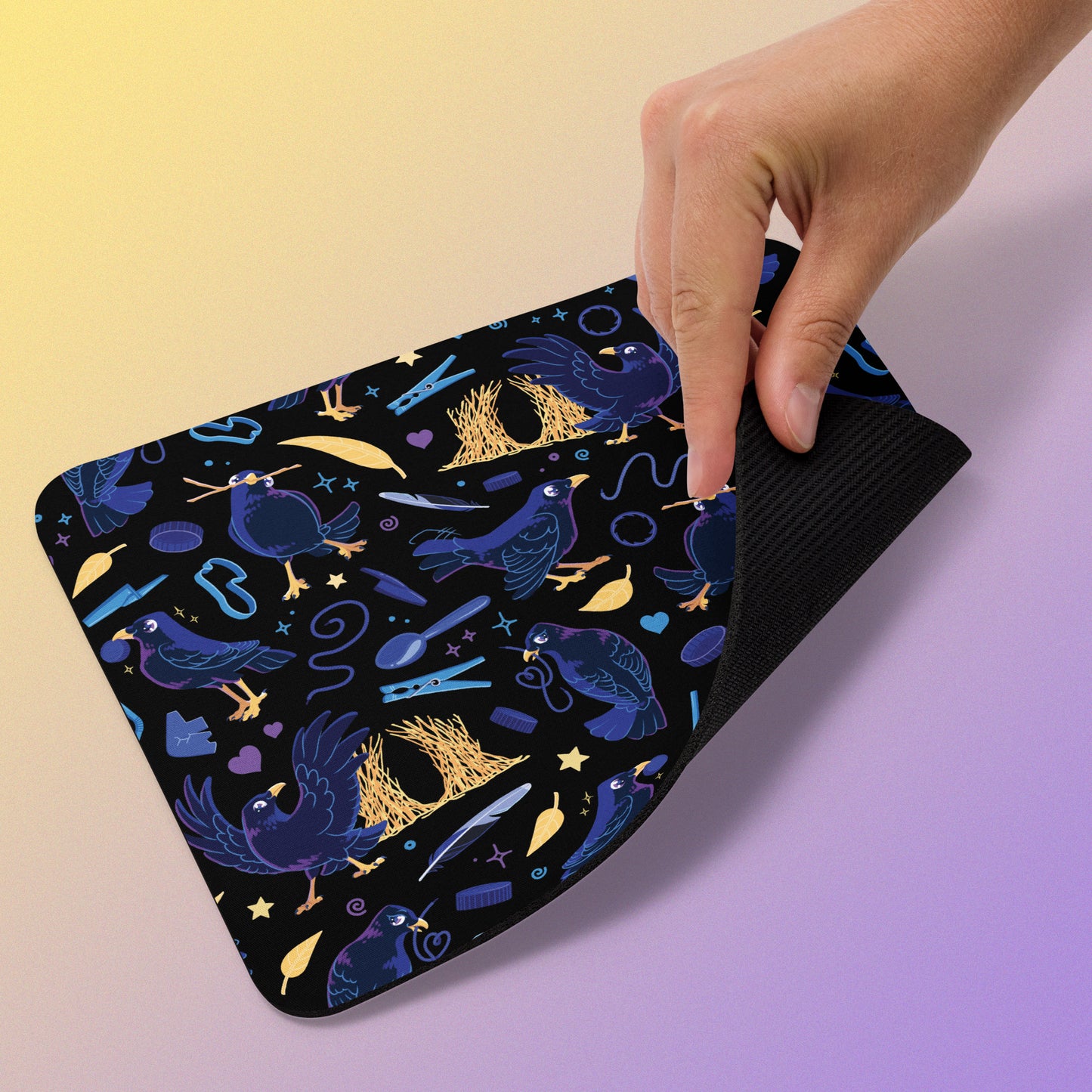 Dark blue-black mouse pad with a colourful satin bowerbird pattern held by a hand on a gradient background