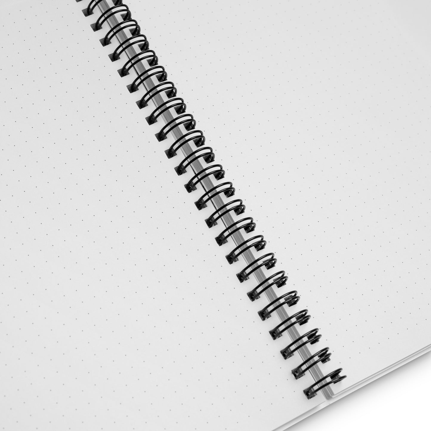 Close up of a spiral-bound notebook with dotted pages on a white background.