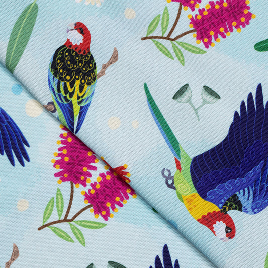 Closeup of a folded tea towel with a rainbow eastern rosellas pattern.