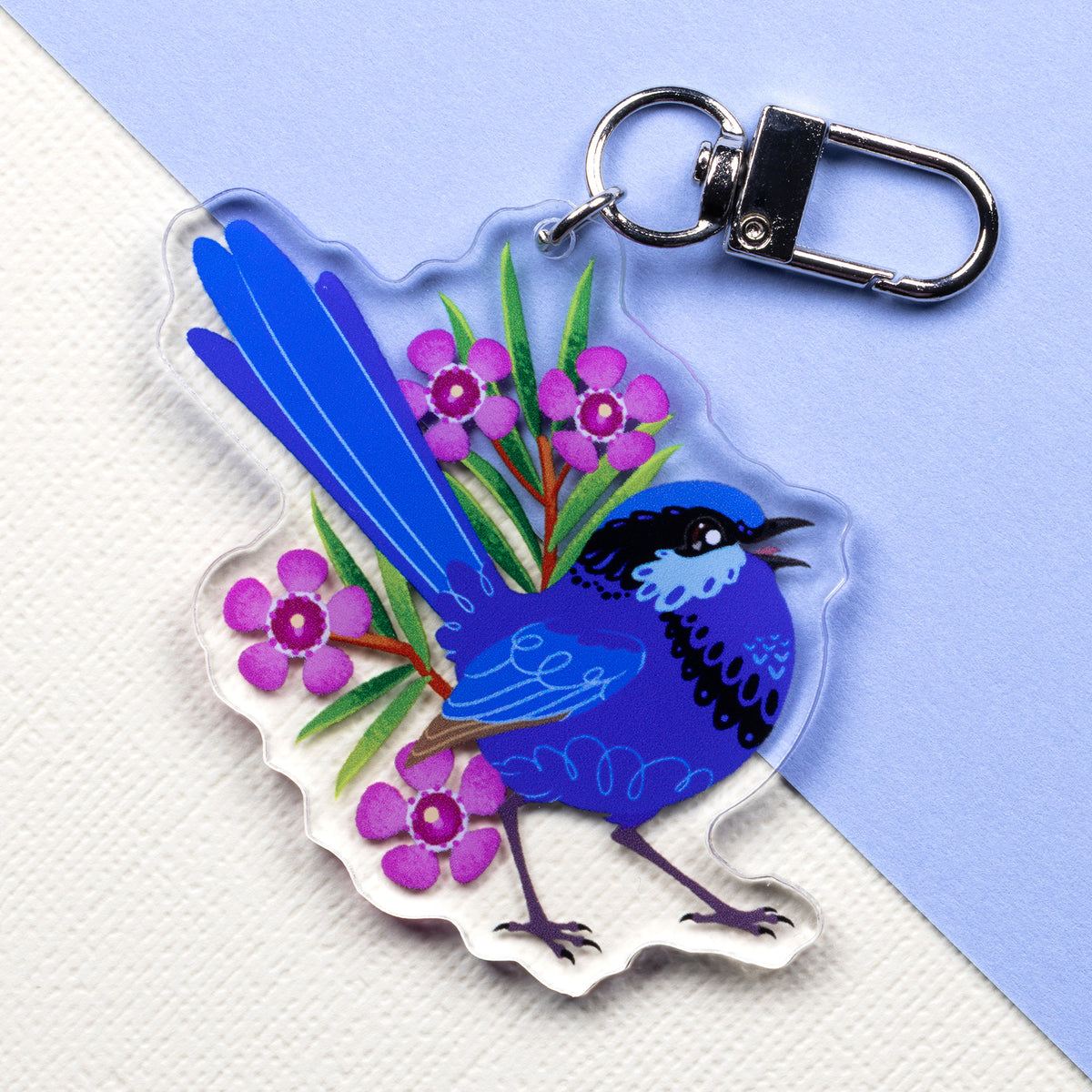 Double-sided acrylic keychain of male & female splendid fairywrens sitting on a split cream and pale blue background.