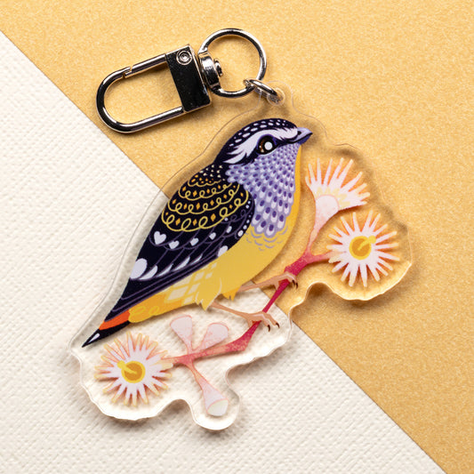 Double-sided acrylic keychain of male & female spotted pardalotes sitting on a split cream & metallic gold background. 