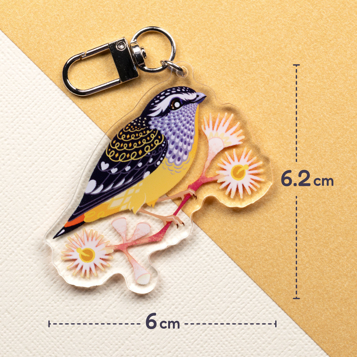 6x6.2cm double-sided acrylic keychain of male & female spotted pardalotes sitting on a split cream & metallic gold background. 