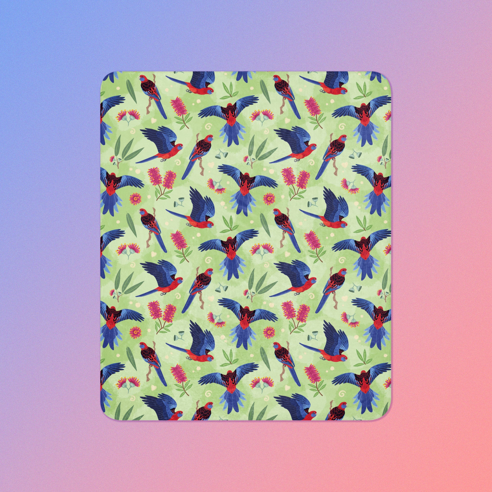 A green, red and blue crimson rosella & native Aussie plant pattern blanket on a blue and pink gradient background.