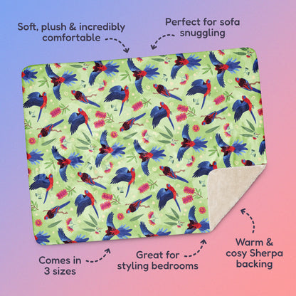 Features & benefits ('Soft, plush & incredibly comfortable', 'Perfect for sofa snuggling', 'Comes in 3 sizes', 'Great for styling bedrooms', 'Warm & cosy Sherpa backing') surrounding a green, red and blue crimson rosella & native Aussie plant pattern blanket on a blue and pink gradient background.