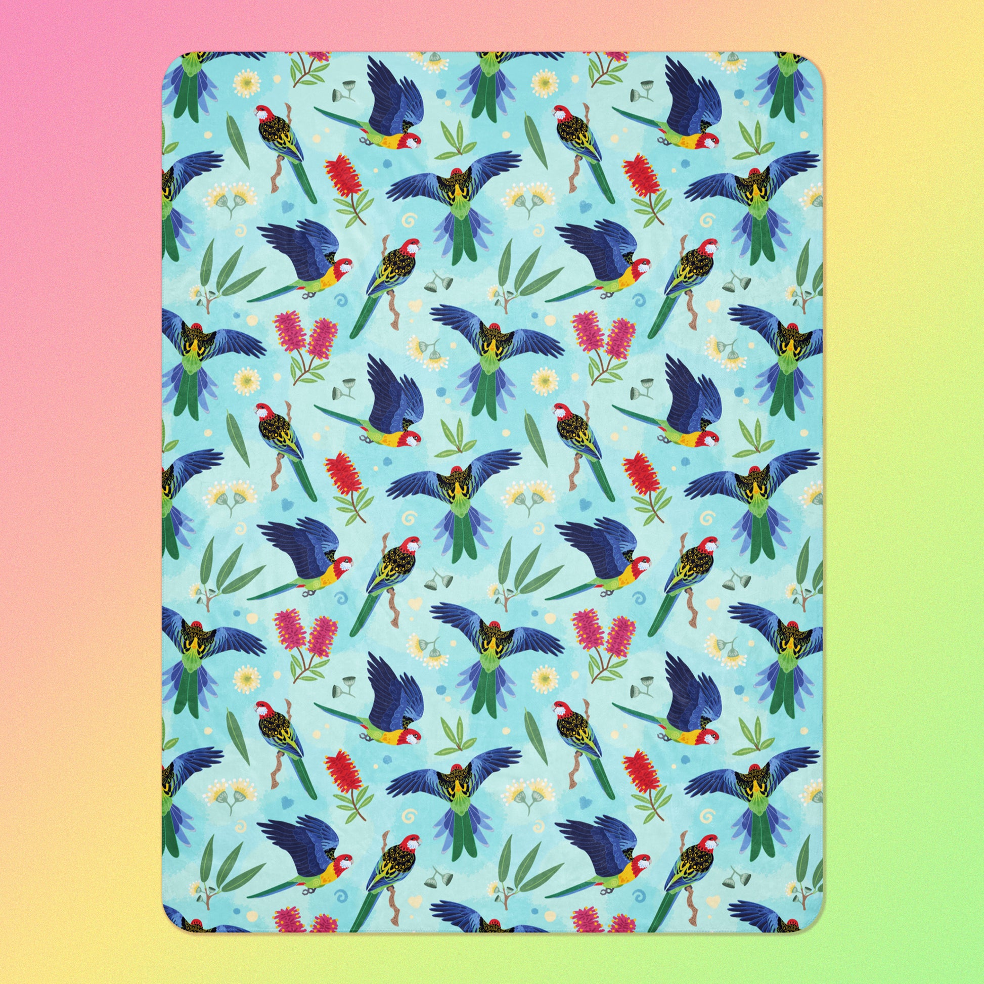 A blue, pink and green eastern rosella & native Aussie plant pattern blanket on a pink, yellow and green gradient background.