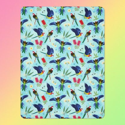 A blue, pink and green eastern rosella & native Aussie plant pattern blanket on a pink, yellow and green gradient background.