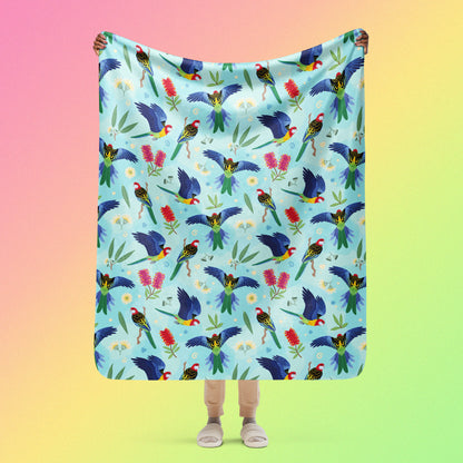 Person holding a blue, pink and green eastern rosella & native Aussie plant pattern blanket above their head on a pink, yellow and green gradient background.