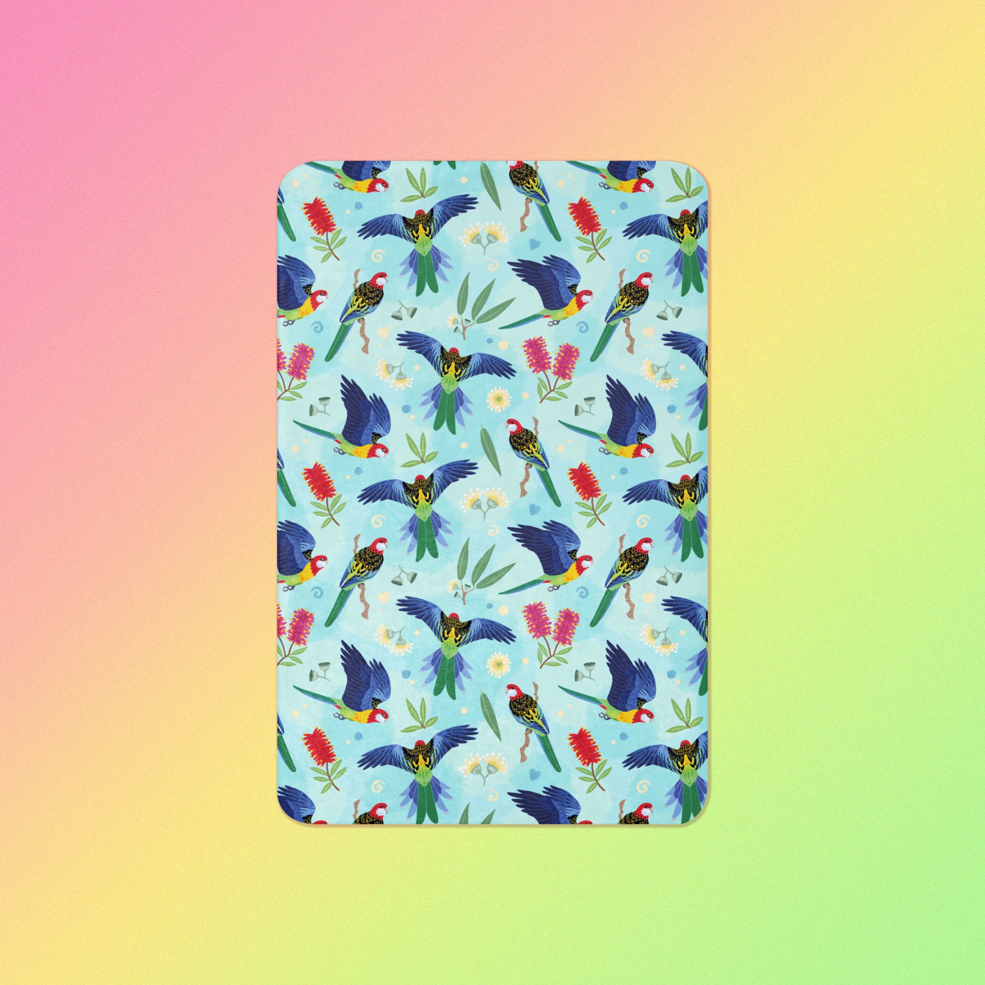 A blue, pink and green eastern rosella & native Aussie plant pattern blanket on a pink, yellow and green gradient background.