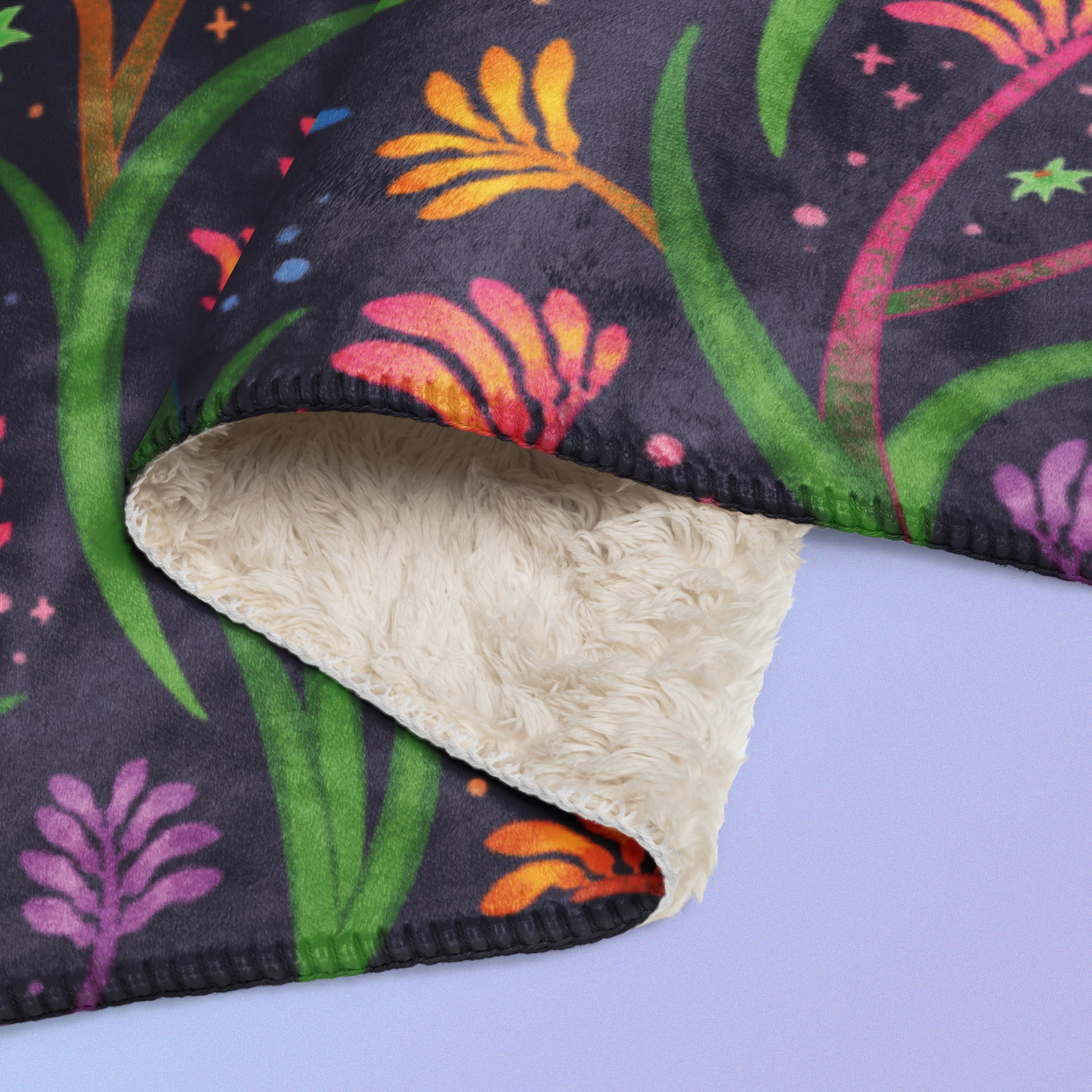Close up detail of a folded rainbow kangaroo paw flower pattern blanket on a blue and purple gradient background.