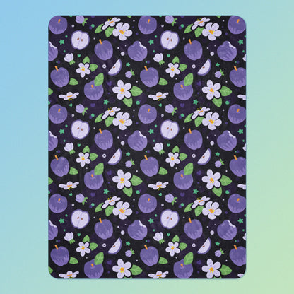 A purple apples & blossoms pattern blanket on a blue and green gradient background.