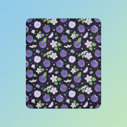 A purple apples & blossoms pattern blanket on a blue and green gradient background.