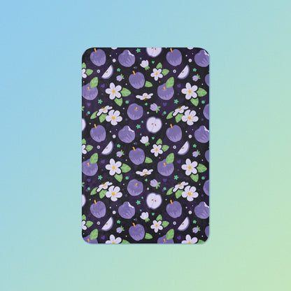 A purple apples & blossoms pattern blanket on a blue and green gradient background.