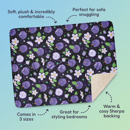 Features & benefits ('Soft, plush & incredibly comfortable', 'Perfect for sofa snuggling', 'Comes in 3 sizes', 'Great for styling bedrooms', 'Warm & cosy Sherpa backing') surrounding a purple apples & blossoms pattern blanket on a blue and green gradient background.