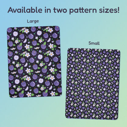 Side-by-side comparison of two pattern print sizes (Large & Small) of a purple apples & blossoms pattern blanket on a blue and green gradient background.