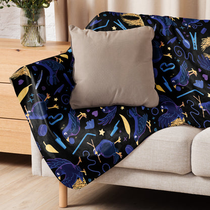 A black, blue, purple and yellow male Aussie satin bowerbird pattern blanket sitting on a beige sofa with a beige pillow on top.
