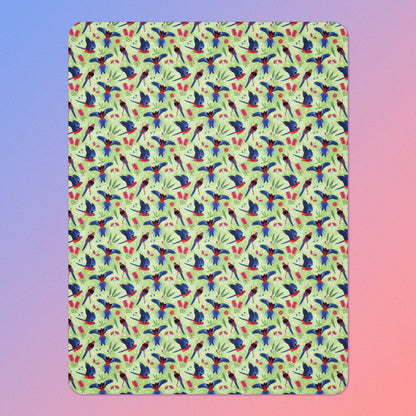 A green, red and blue crimson rosella & native Aussie plant pattern blanket on a blue and pink gradient background.