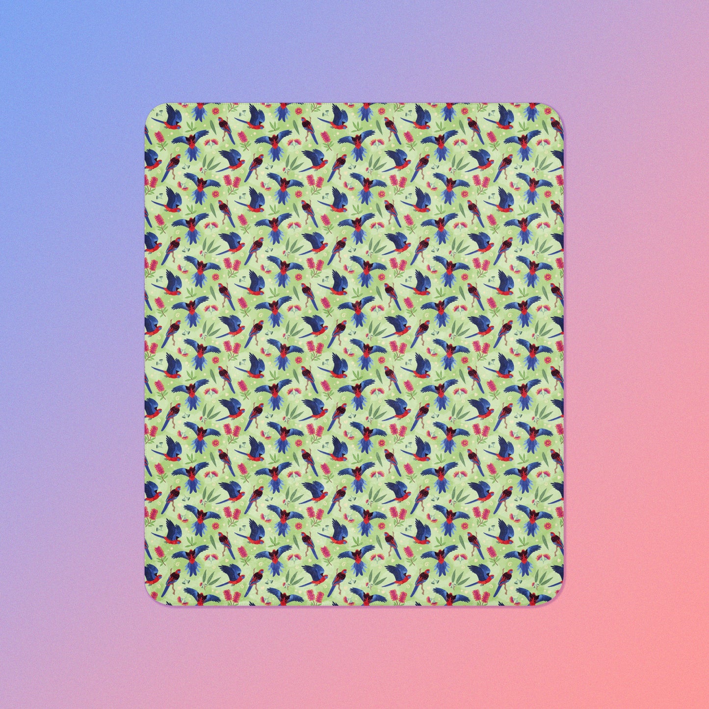 A green, red and blue crimson rosella & native Aussie plant pattern blanket on a blue and pink gradient background.