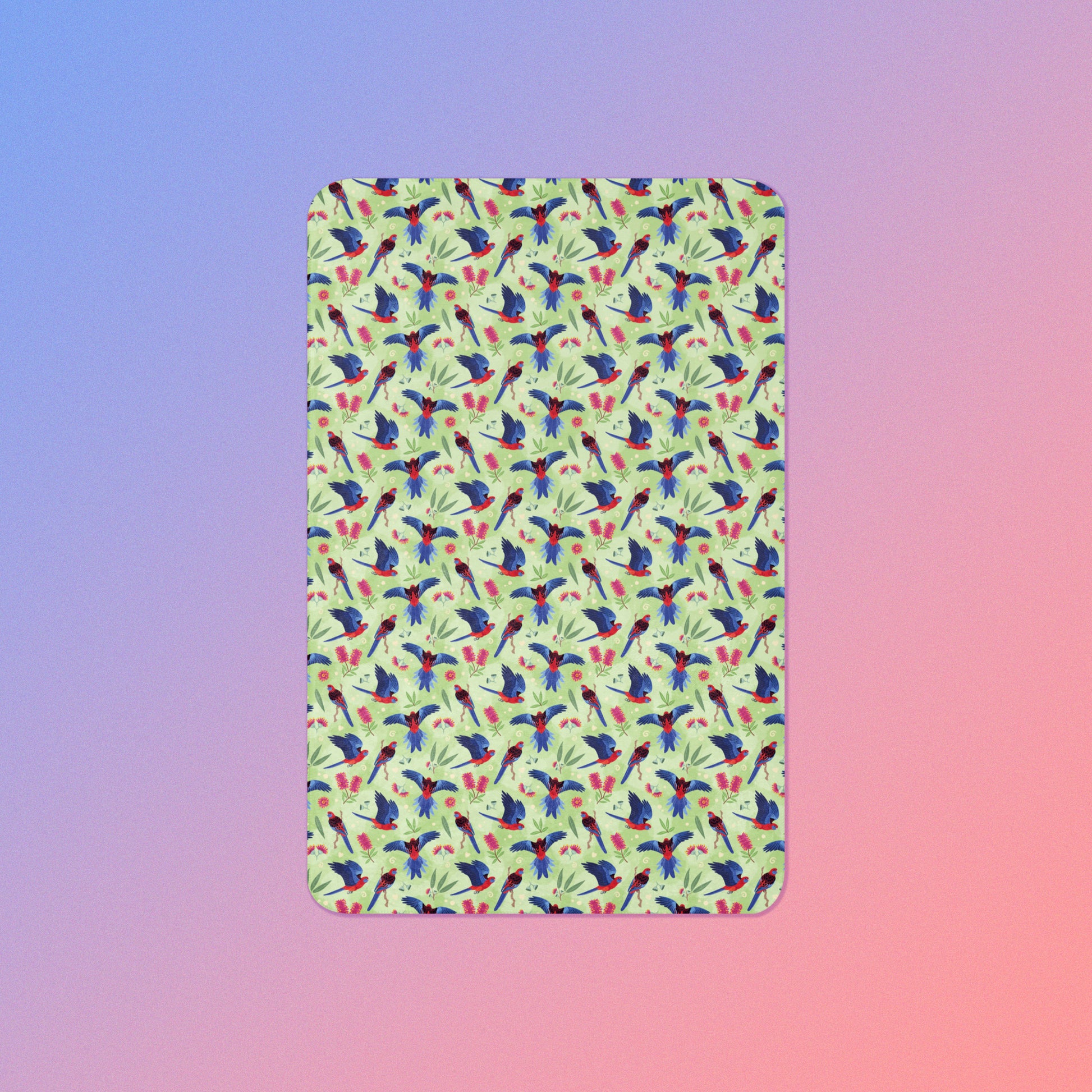 A green, red and blue crimson rosella & native Aussie plant pattern blanket on a blue and pink gradient background.
