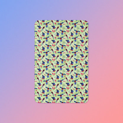 A green, red and blue crimson rosella & native Aussie plant pattern blanket on a blue and pink gradient background.