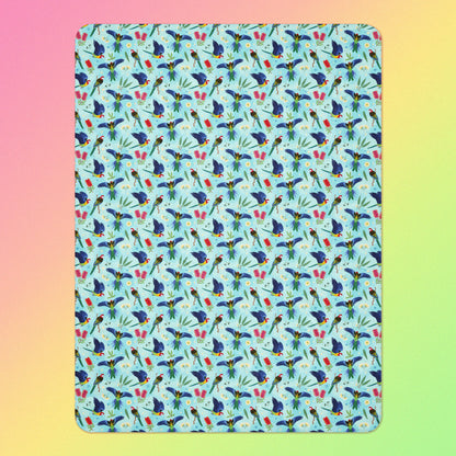 A blue, pink and green eastern rosella & native Aussie plant pattern blanket on a pink, yellow and green gradient background.