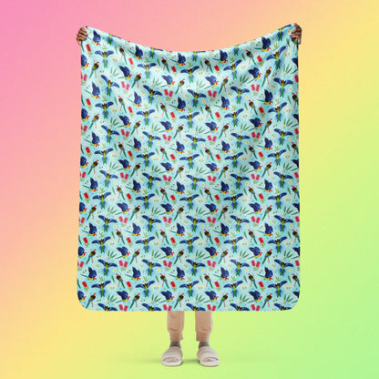 Person holding a blue, pink and green eastern rosella & native Aussie plant pattern blanket above their head on a pink, yellow and green gradient background.