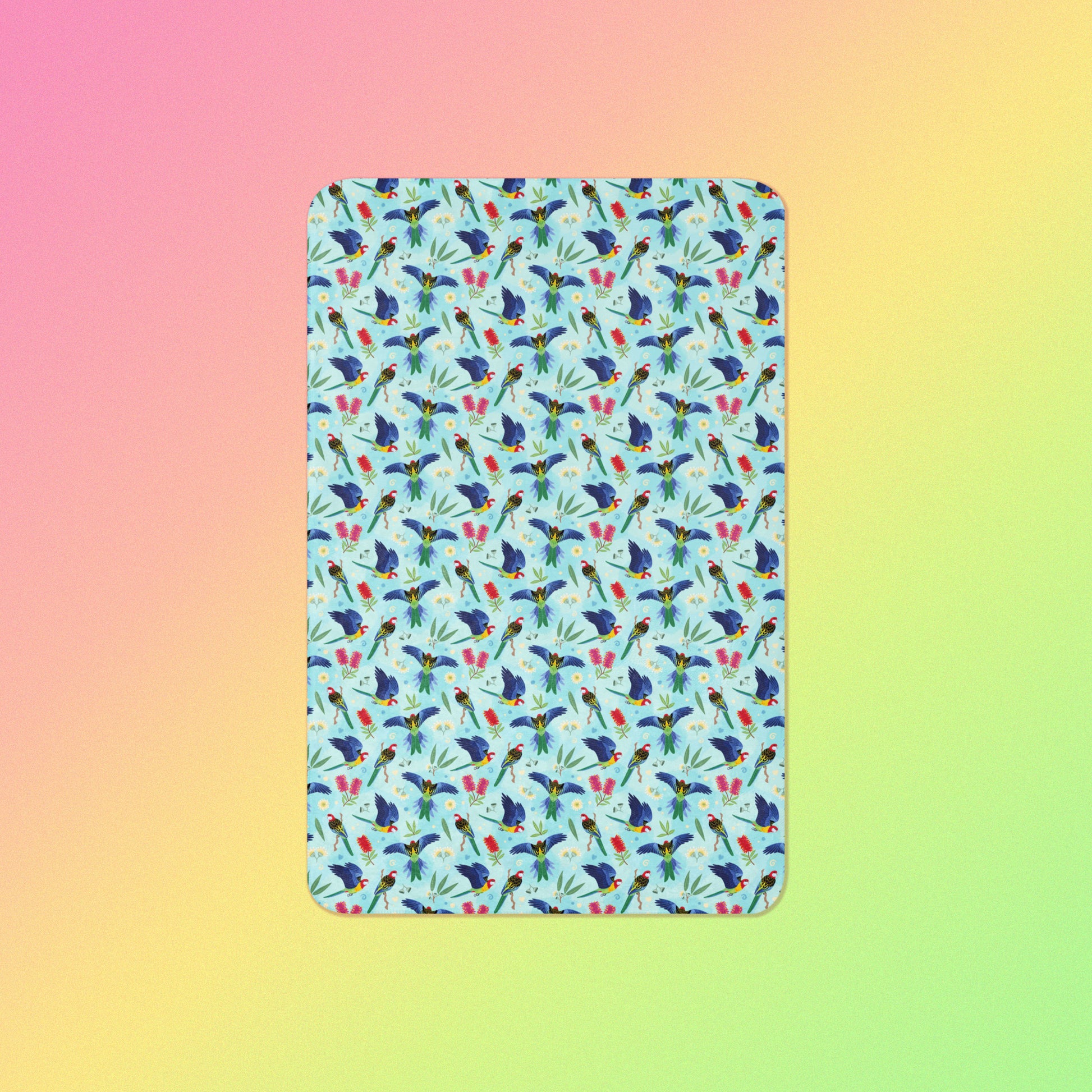 A blue, pink and green eastern rosella & native Aussie plant pattern blanket on a pink, yellow and green gradient background.