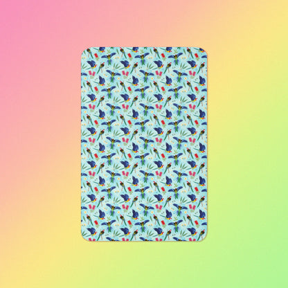 A blue, pink and green eastern rosella & native Aussie plant pattern blanket on a pink, yellow and green gradient background.