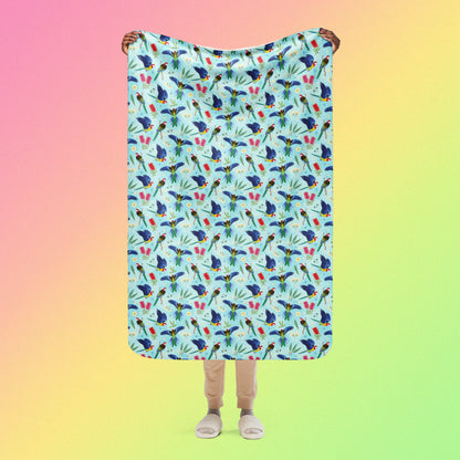Person holding a blue, pink and green eastern rosella & native Aussie plant pattern blanket above their head on a pink, yellow and green gradient background.