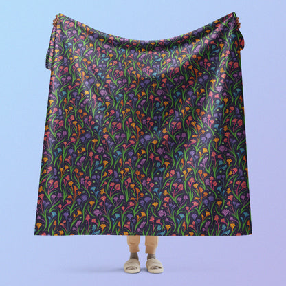 Person holding a rainbow kangaroo paw flower pattern blanket above their head on a blue and purple gradient background.