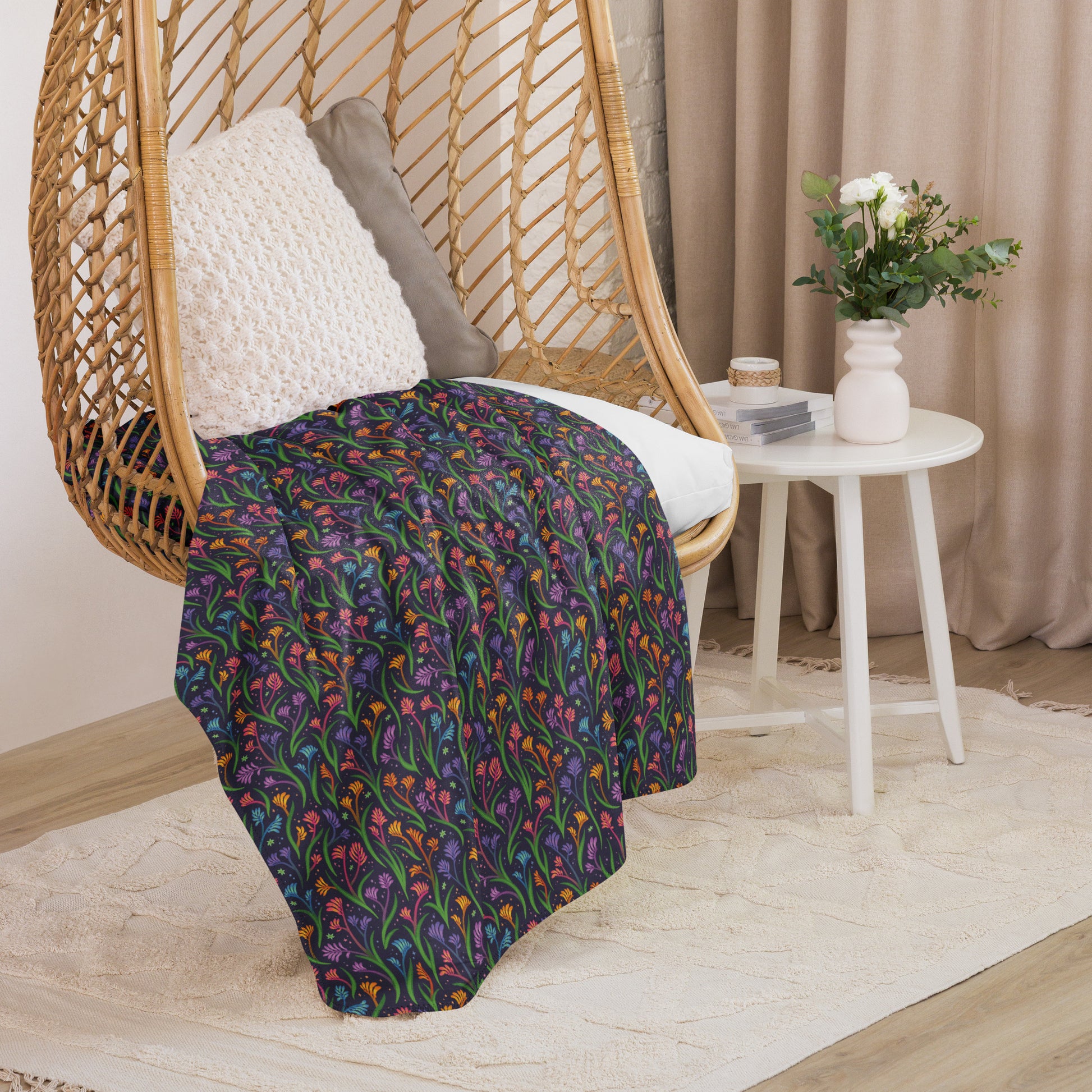 A rainbow kangaroo paw flower pattern blanket sitting on a swinging woven egg chair with soft, natural lighting.