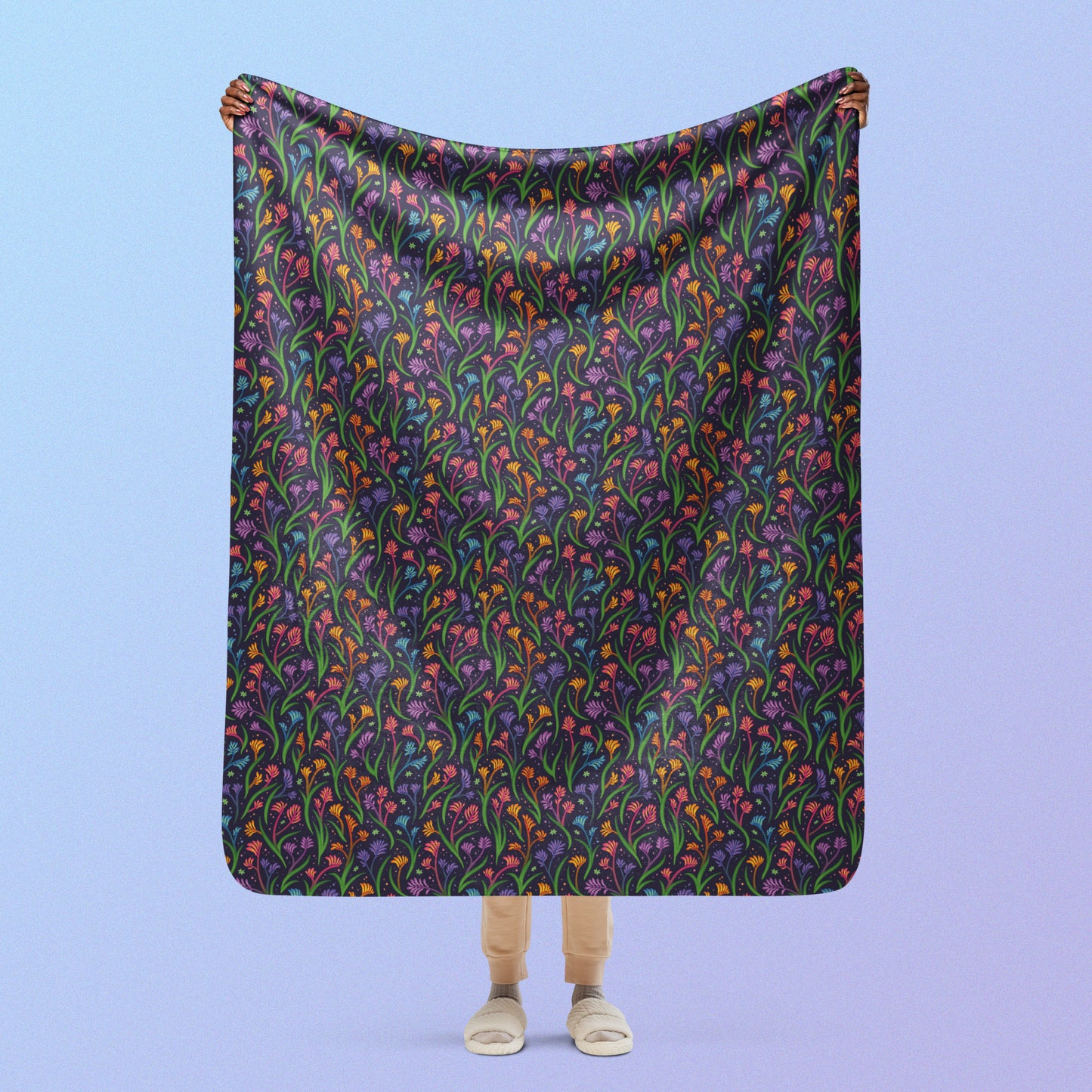 Person holding a rainbow kangaroo paw flower pattern blanket above their head on a blue and purple gradient background.