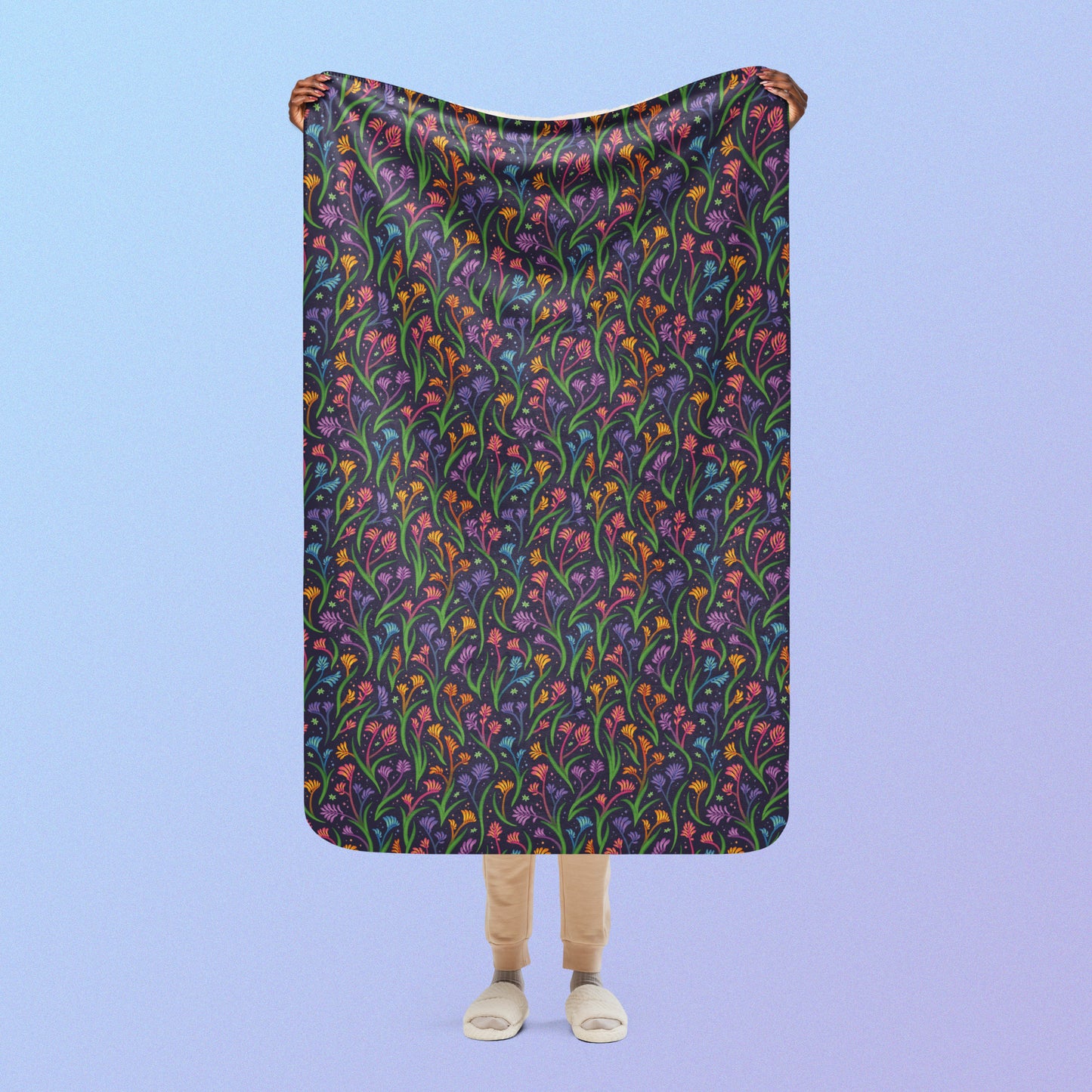 Person holding a rainbow kangaroo paw flower pattern blanket above their head on a blue and purple gradient background.