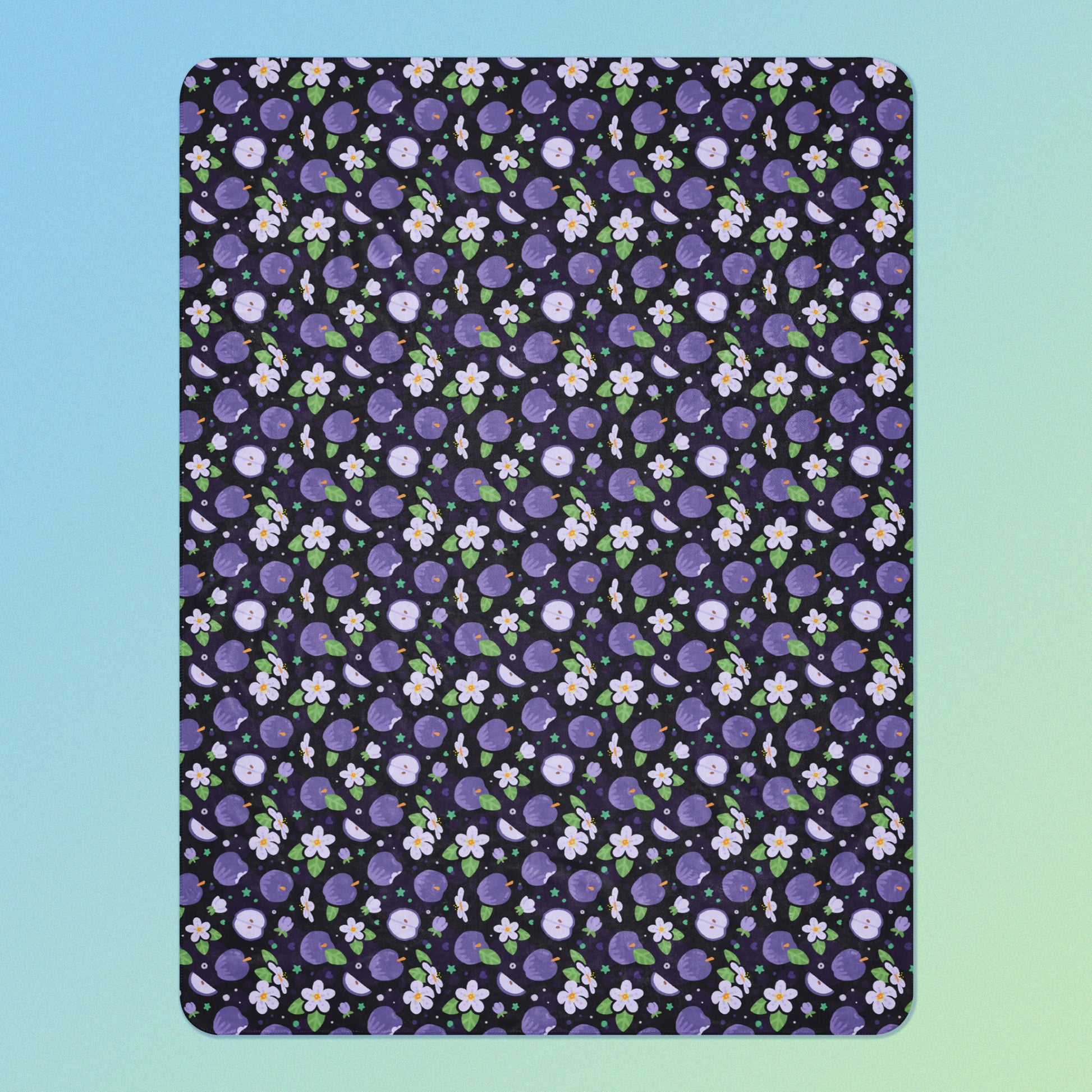 A purple apples & blossoms pattern blanket on a blue and green gradient background.