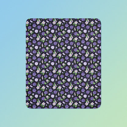 A purple apples & blossoms pattern blanket on a blue and green gradient background.