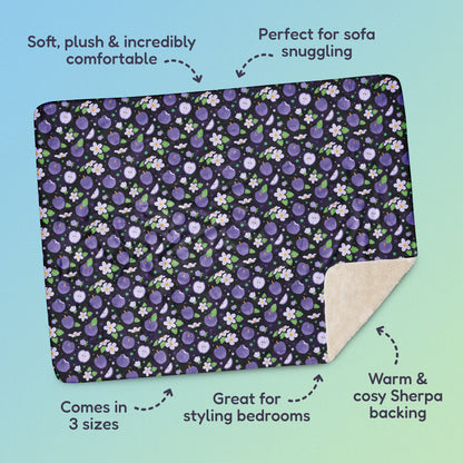 Features & benefits ('Soft, plush & incredibly comfortable', 'Perfect for sofa snuggling', 'Comes in 3 sizes', 'Great for styling bedrooms', 'Warm & cosy Sherpa backing') surrounding a purple apples & blossoms pattern blanket on a blue and green gradient background.