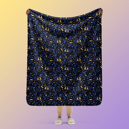 Person holding a black, blue, purple and yellow male Aussie satin bowerbird pattern blanket above their head on a yellow and purple gradient background.