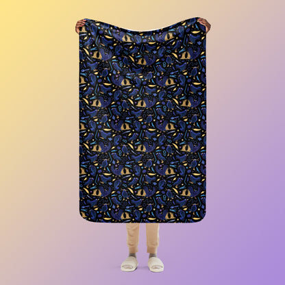 Person holding a black, blue, purple and yellow male Aussie satin bowerbird pattern blanket above their head on a yellow and purple gradient background.