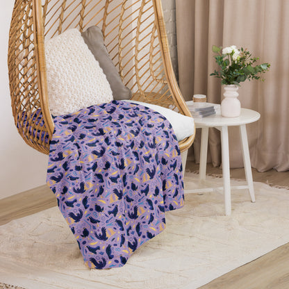 A purple, blue and yellow male Aussie satin bowerbird pattern blanket sitting on a swinging woven egg chair with soft, natural lighting.