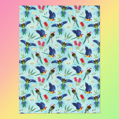 A blue, pink and green eastern rosella & native Aussie plant pattern blanket on a pink, yellow and green gradient background.