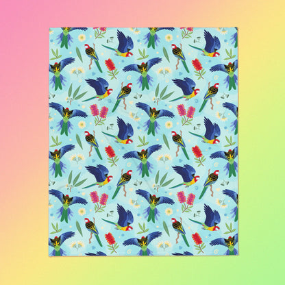 A blue, pink and green eastern rosella & native Aussie plant pattern blanket on a pink, yellow and green gradient background.