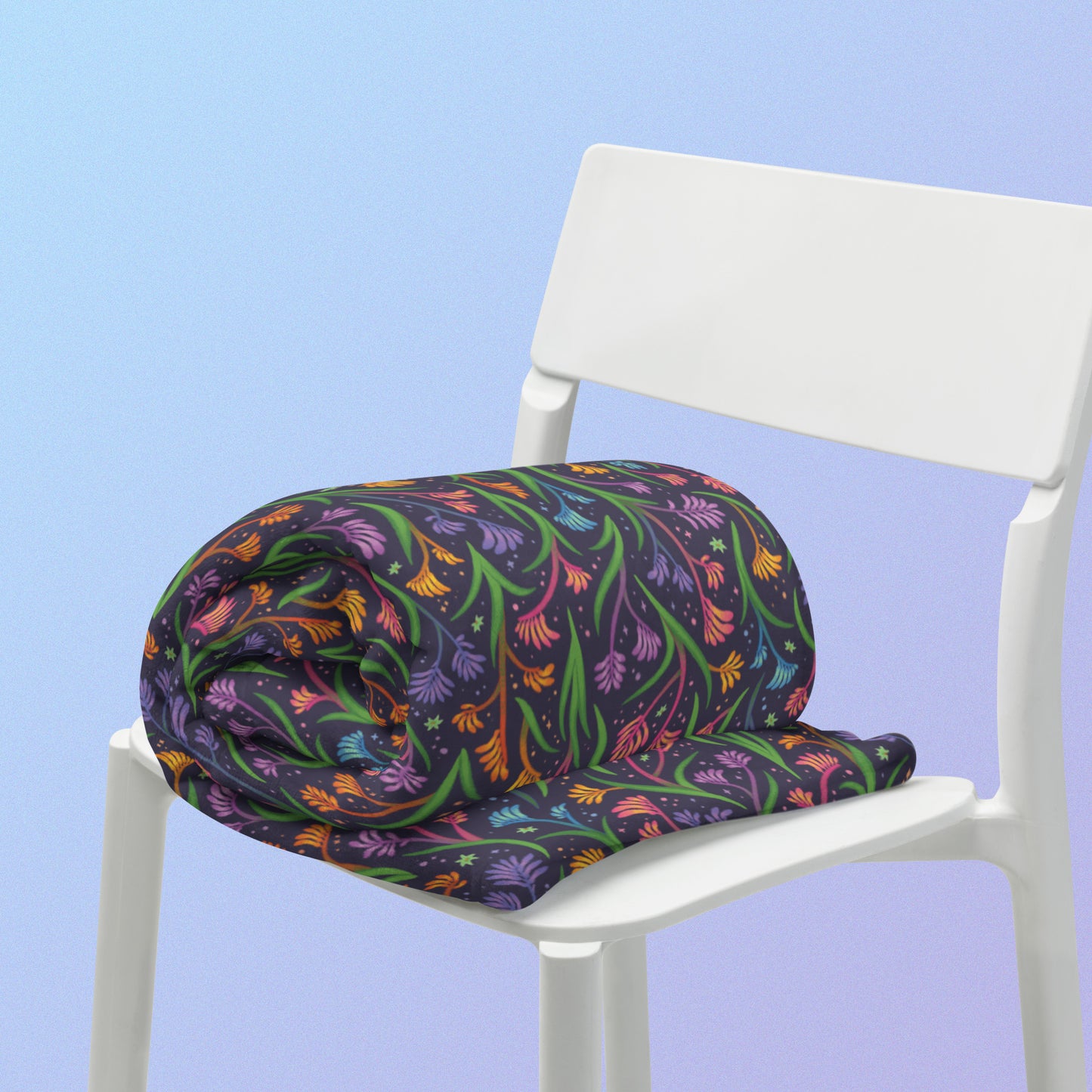 A rolled up rainbow kangaroo paw flower pattern blanket sitting on a white chair on a blue and purple gradient background.