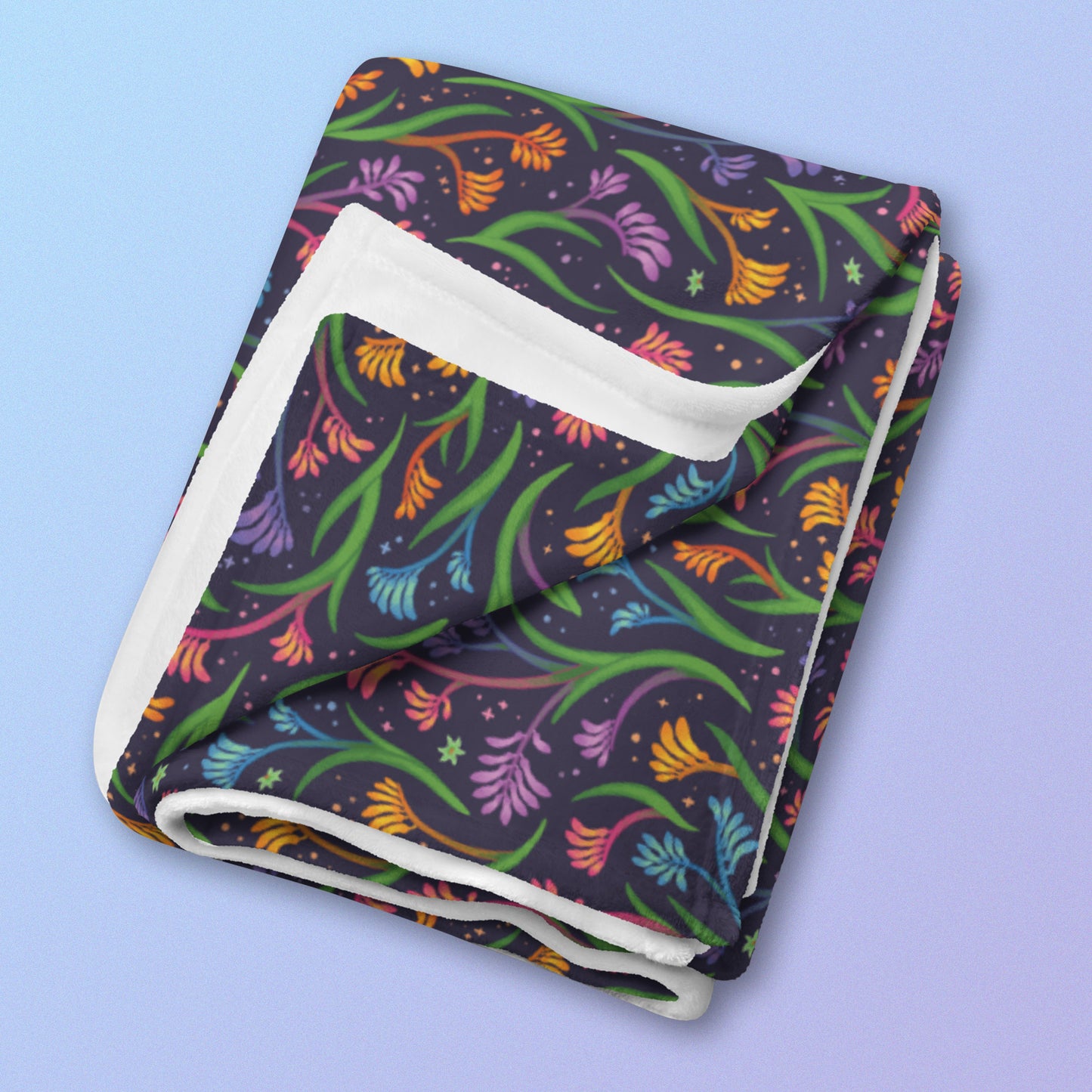 A folded rainbow kangaroo paw flower pattern blanket on a blue and purple gradient background.