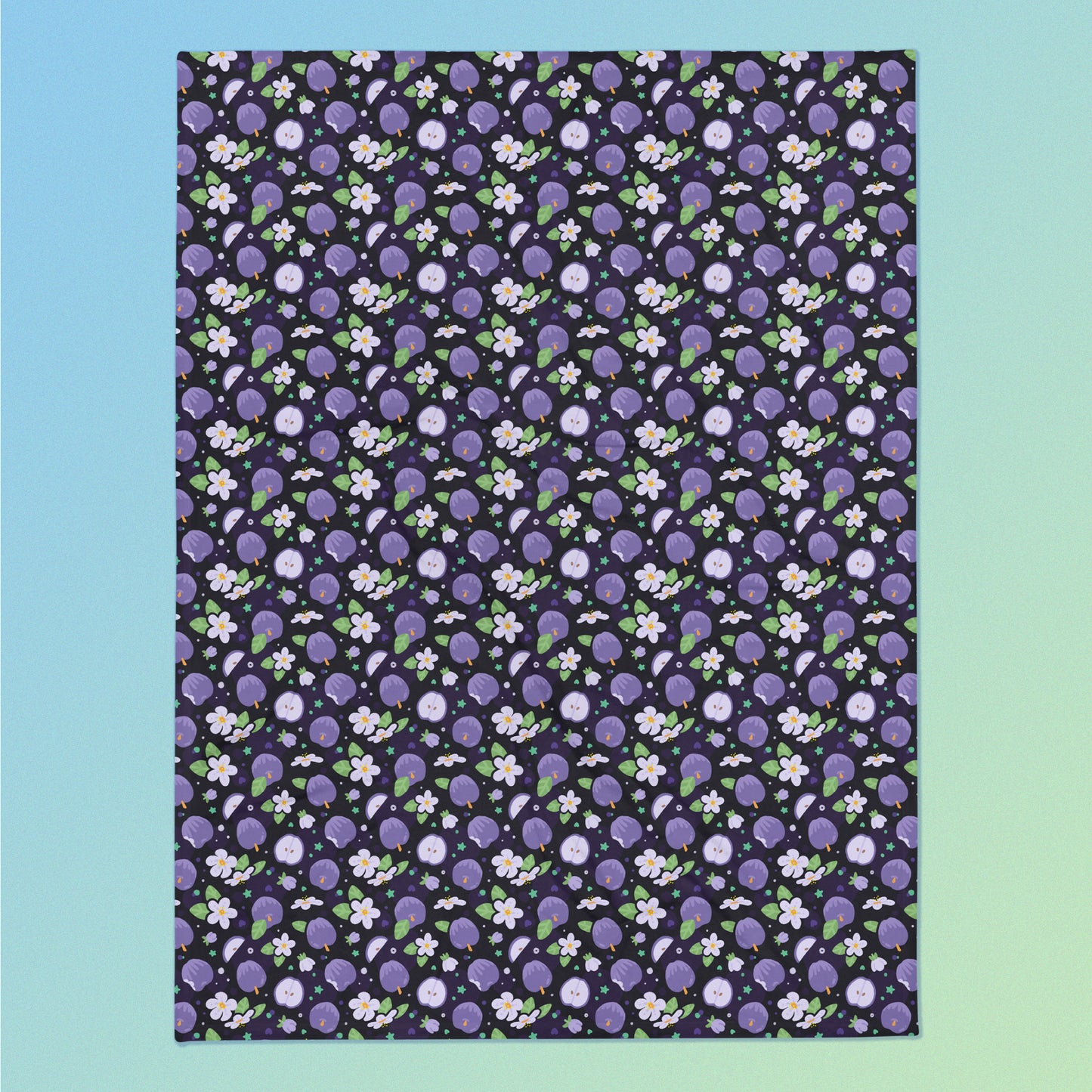 A purple apples & blossoms pattern blanket on a blue and green gradient background.
