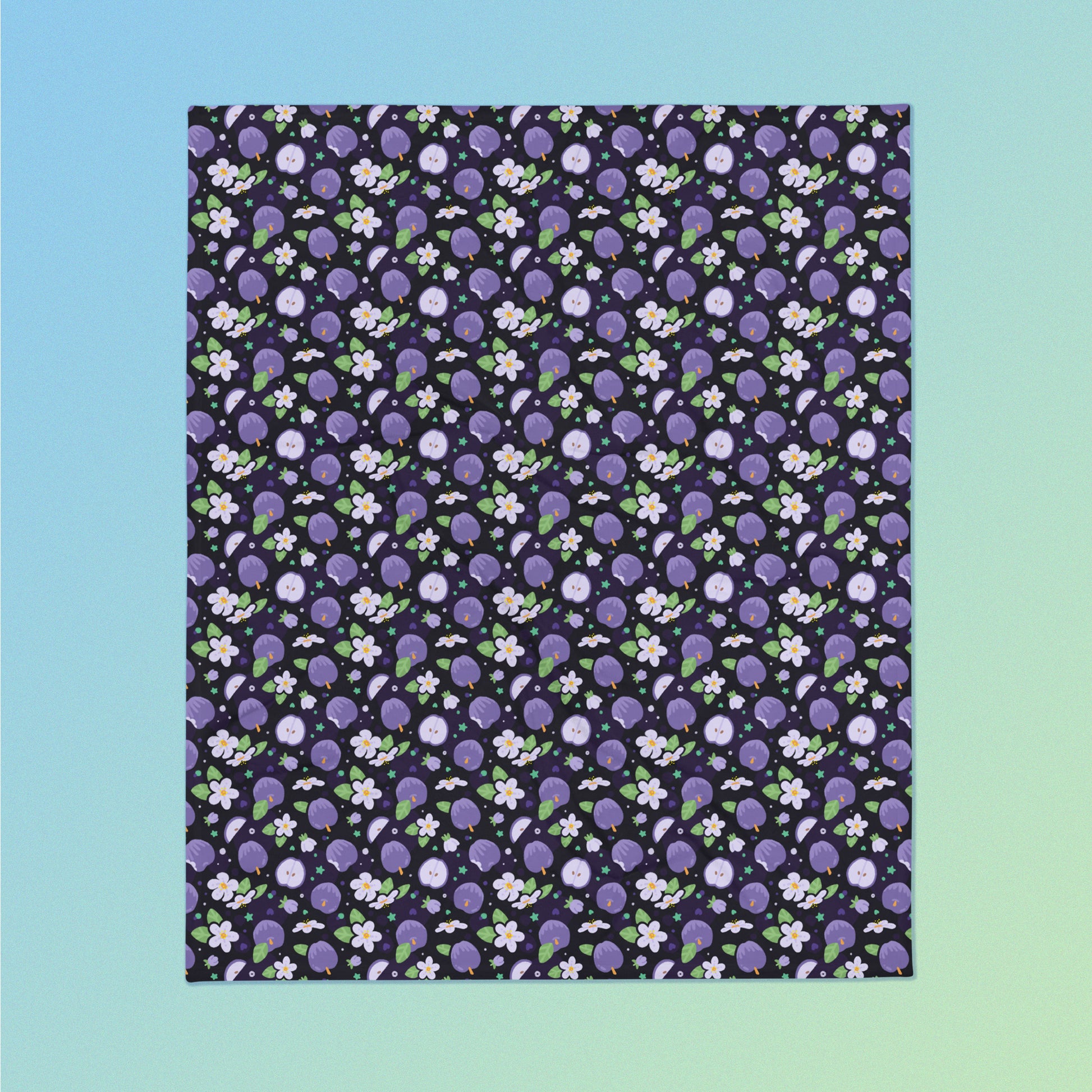 A purple apples & blossoms pattern blanket on a blue and green gradient background.