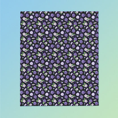 A purple apples & blossoms pattern blanket on a blue and green gradient background.