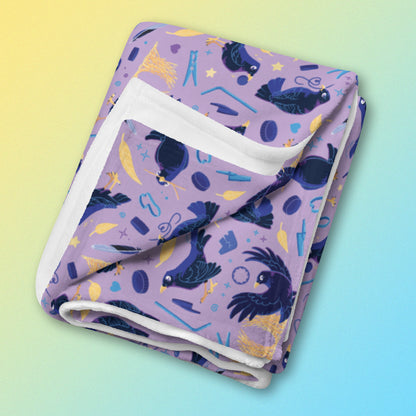 A folded purple, blue and yellow male Aussie satin bowerbird pattern blanket on a yellow and blue gradient background.