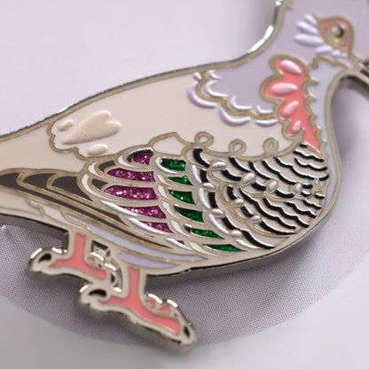 Closeup of a a nickel-plated crested pigeon hard enamel pin on a white background.