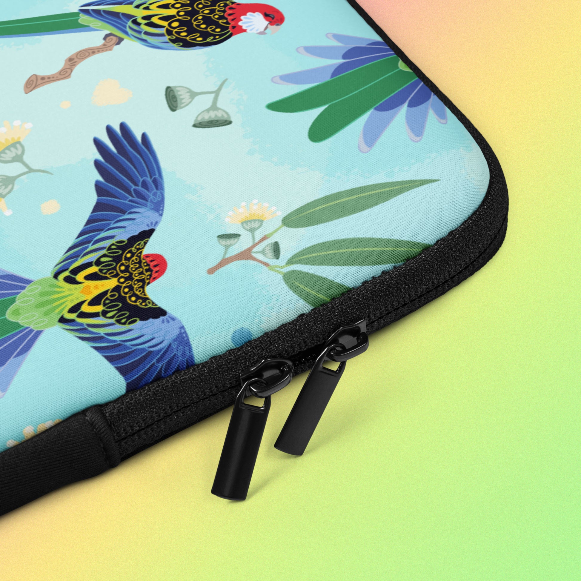 Close up detail of a laptop sleeve with a colourful rainbow, blue, green, red and pink Eastern Rosella pattern on a pink, yellow and green gradient background.