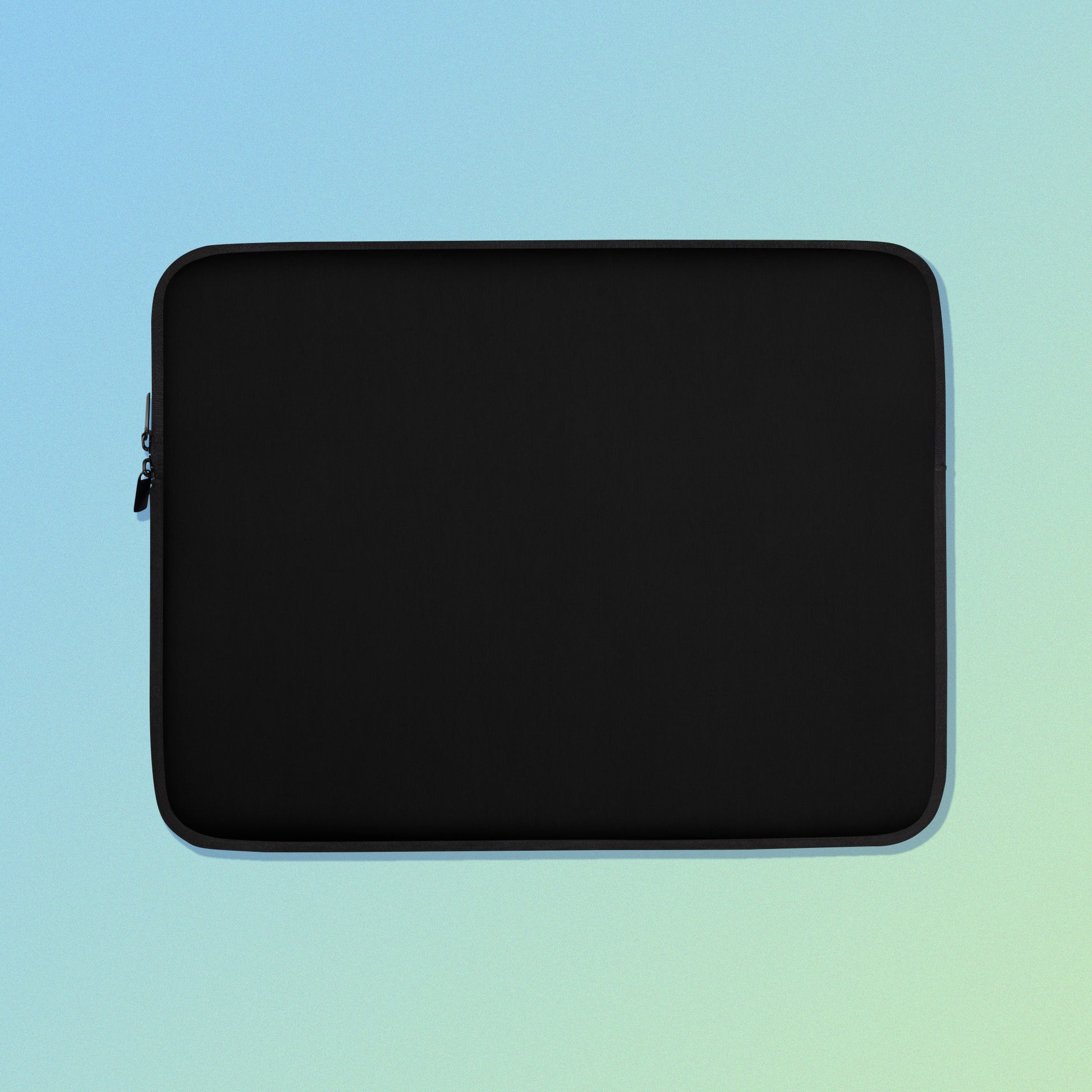 Laptop sleeve with plain black fabric on one side and a colourful purple apples and apple blossoms pattern on the other on a blue and green gradient background.