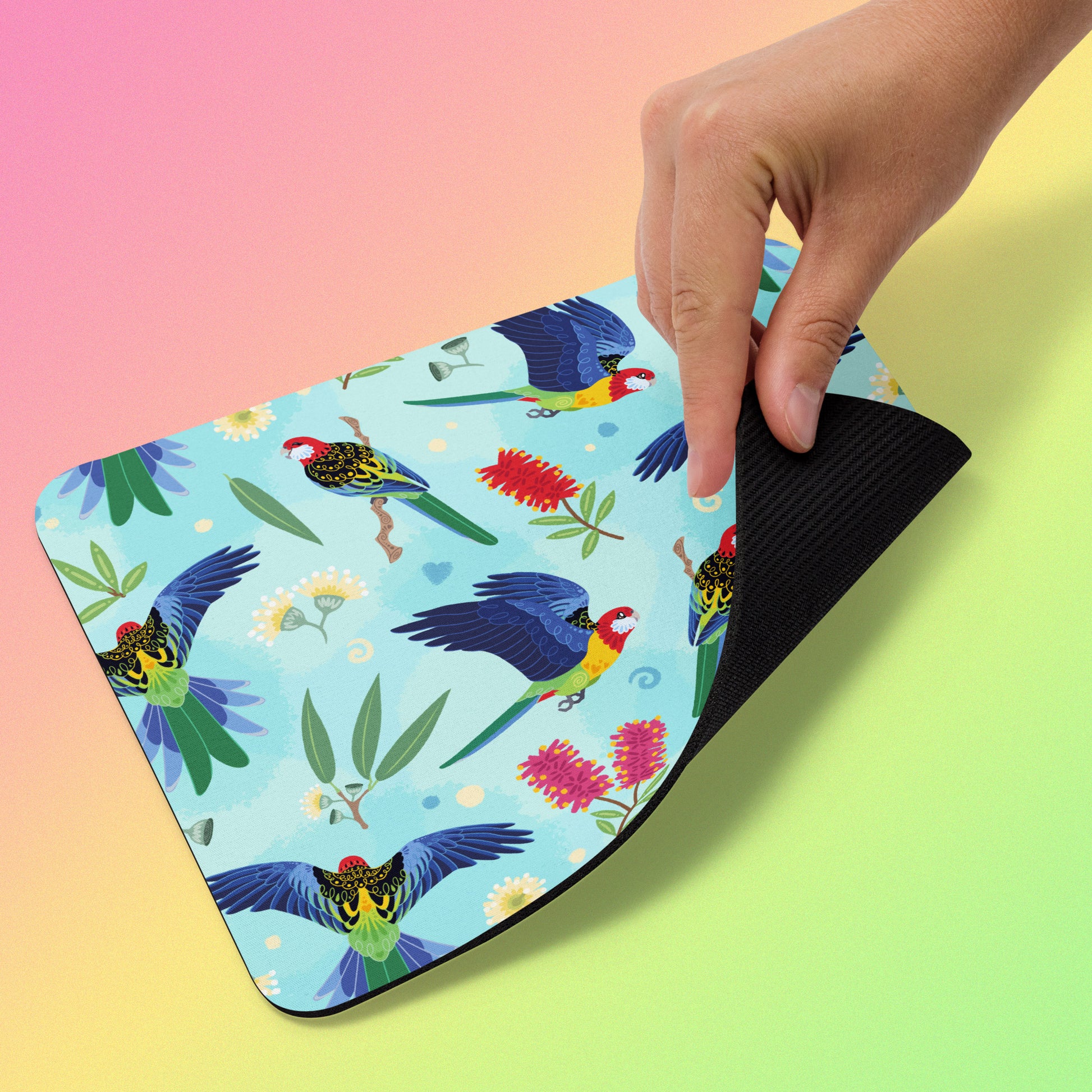 Mouse pad with an eastern rosella parrot design held by a hand on a gradient background